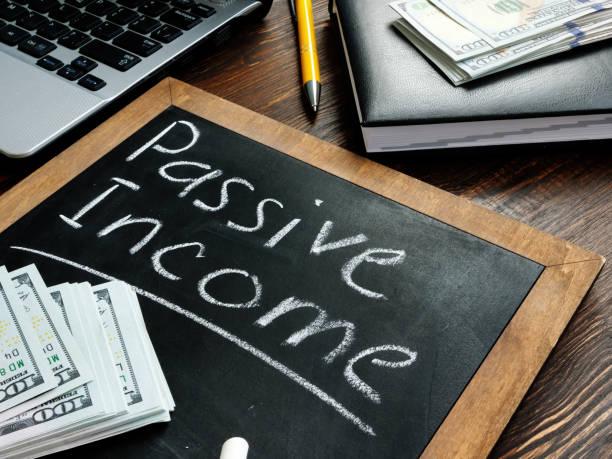 Passive income inscription on the board and a bundle of bills